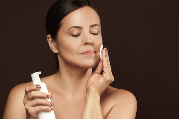 wiping skin with toner cotton pad before self tanner application to remove excess oil