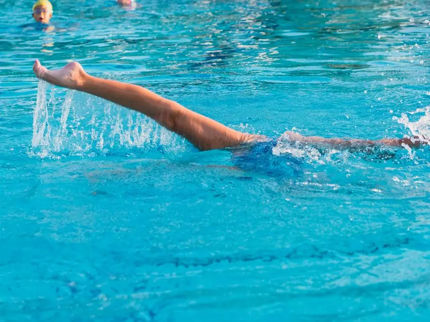 Dynamic shot of a swimmer's arm slicing through the water in a clear blue swimming pool.